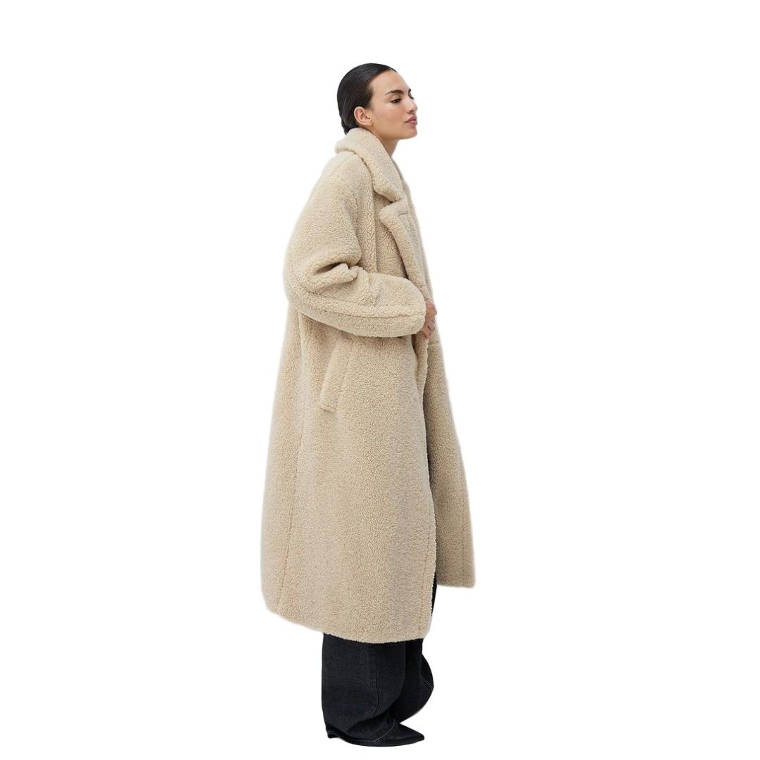 Person wearing a beige coat against a white background