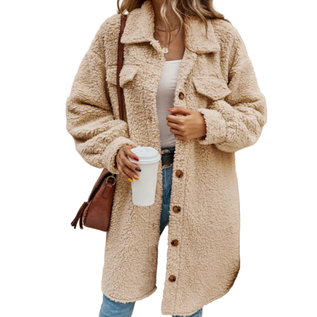 Person wearing a beige teddy coat holding a coffee cup on steps.