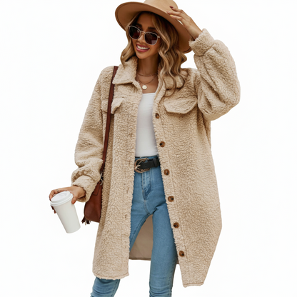 Woman wearing a beige teddy coat, blue jeans, and a brown hat, holding a coffee cup.