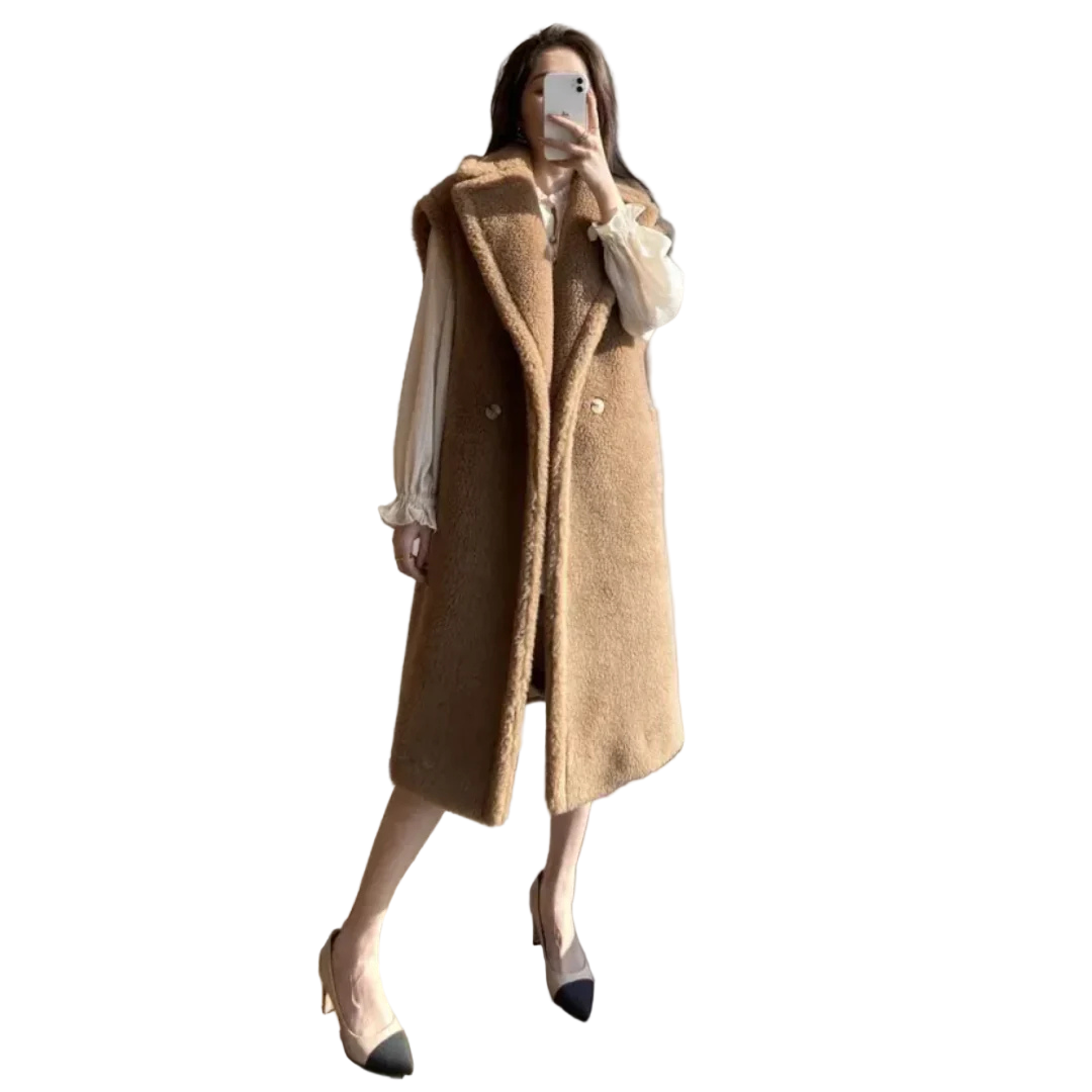 Person wearing a long brown coat in a room with a window.